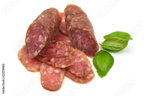 Smoked sausage with thin slices and green basil leaves, isolated on white background
