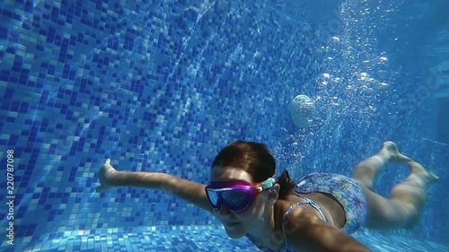 Young girl dive underwater in blue swimming pool. Slow motion 120 FPS.