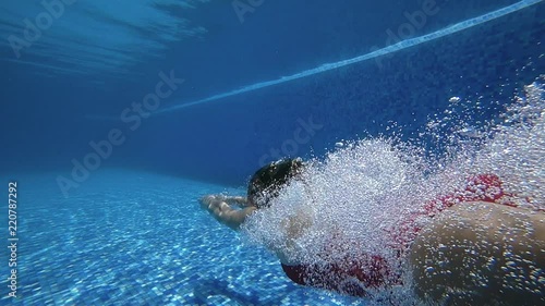 A teenage girl dive in blue swimming pool. Slow motion 120 FPS.