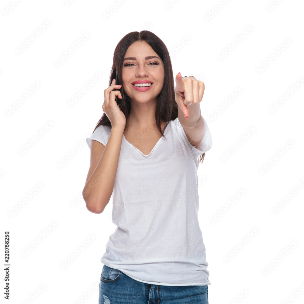 smiling casual woman talking on the phone is pointing finger smiling casual woman talking on the phone is pointing finger
