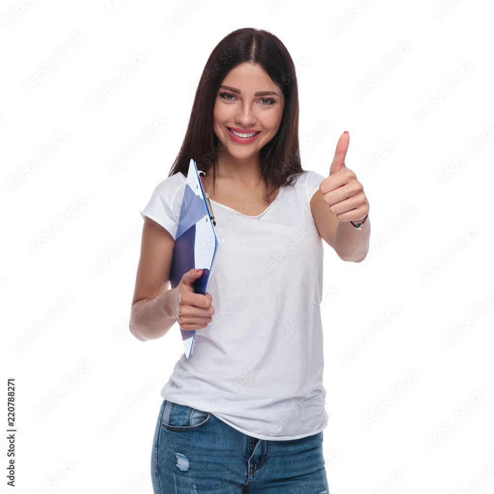 brunette woman holding blue clipboard makes thumbs up sign brunette woman holding blue clipboard makes thumbs up sign