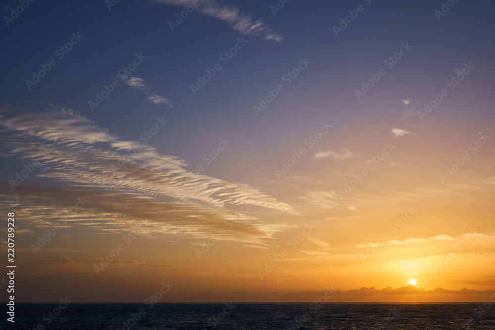 Beautiful sunset at Indian Sea near Maldives seen from a ship with a view of sun, clouds, waves, and violet sky.