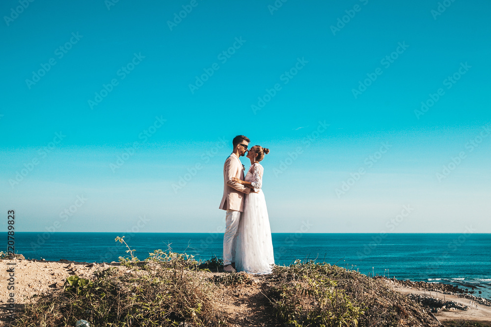 Portrait of bride and groom posing on the cliff behind blue sky and sea. Wedding Couple Portrait of bride and groom posing on the cliff behind blue sky and sea. Wedding Couple