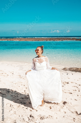 Portrait of  beautiful bride dancing on the beach behind blue sky and sea