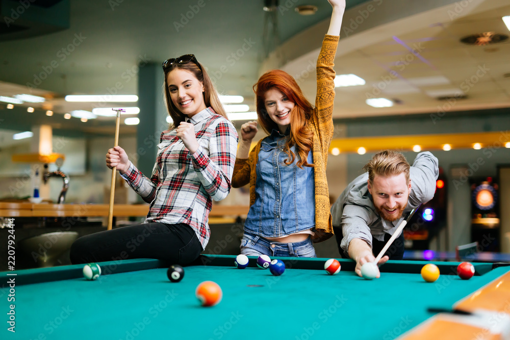 Fototapeta premium Happy friends enjoying playing pool