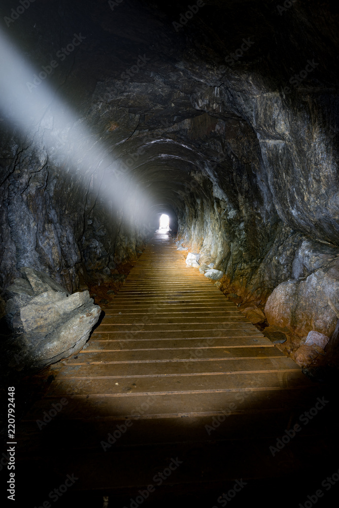 Light from a flashlight shining through a narrow cave in the tow