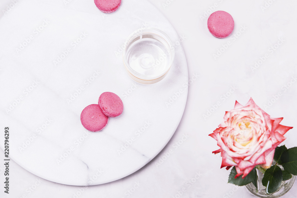 Before Breakfast. Empty glass and pink french cookies macaroons and rose flower on grey marble table and grey concrete background. Top view Before Breakfast. Empty glass and pink french cookies macaroons and rose flower on grey marble table and grey concrete background. Top view