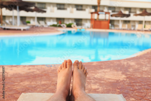 male feet on swimming pool background