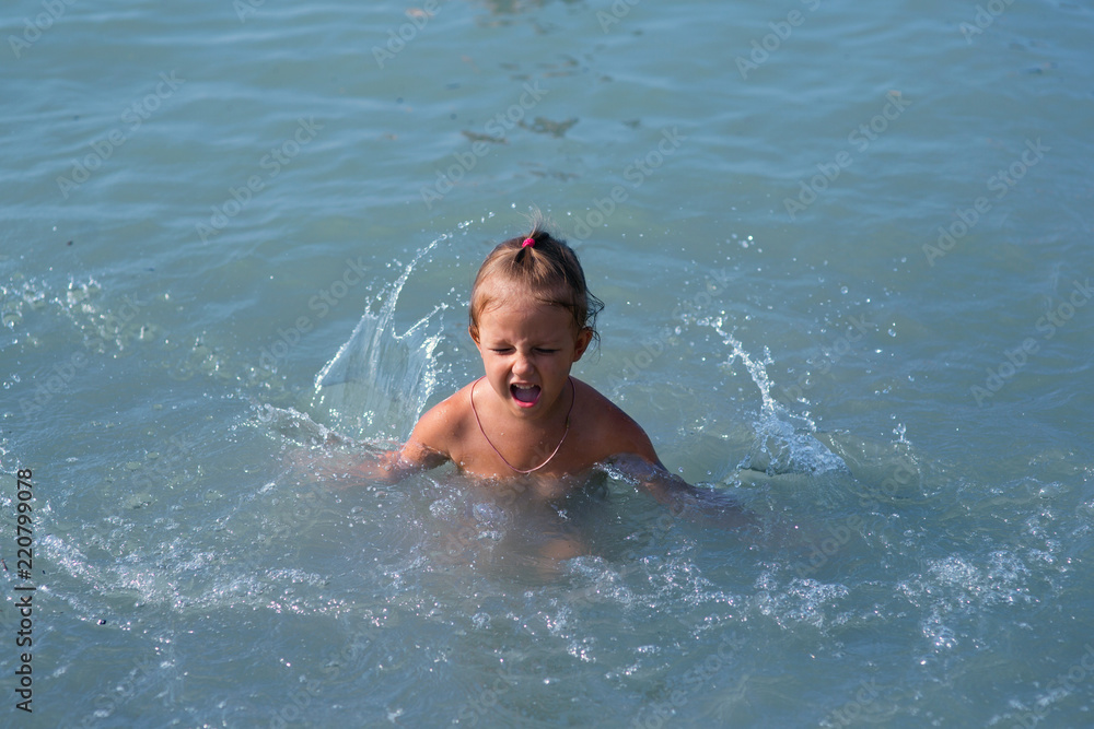 child bathes in the sea