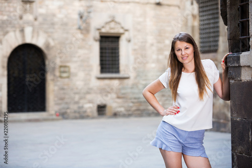 Young woman standing near old stone wall