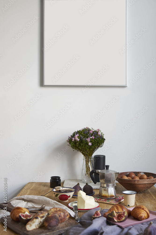 White kitchen interior with breakfast on wooden table, poster on the white wall, space for design layout.