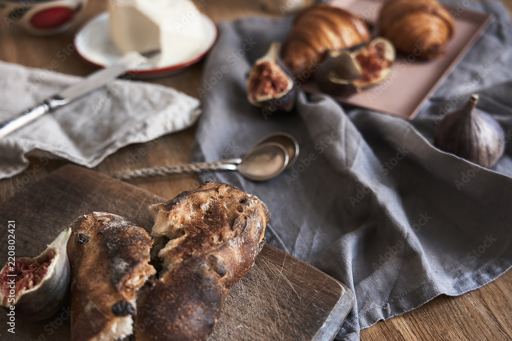 Breakfast with batter & bread, croissants, figs, silver spoons on wooden rustic background, warm colors, close-up Breakfast with batter & bread, croissants, figs, silver spoons on wooden rustic background, warm colors, close-up