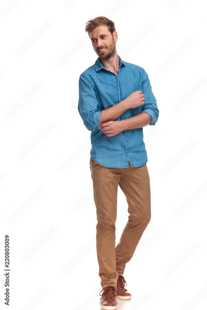 young casual man fixing sleeve and looks to side young casual man fixing sleeve and looks to side