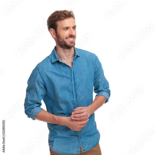smiling casual man with palms together looks to side