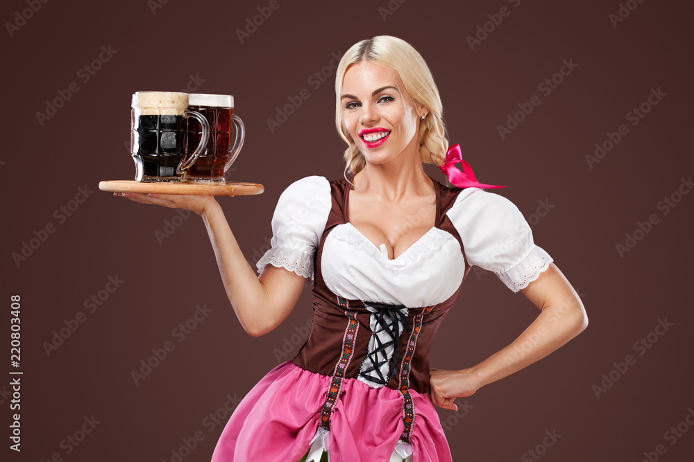 Happy Oktoberfest woman waitress, wearing a traditional Bavarian dress, serving big beer mugs on brown background. Happy Oktoberfest woman waitress, wearing a traditional Bavarian dress, serving big beer mugs on brown background.