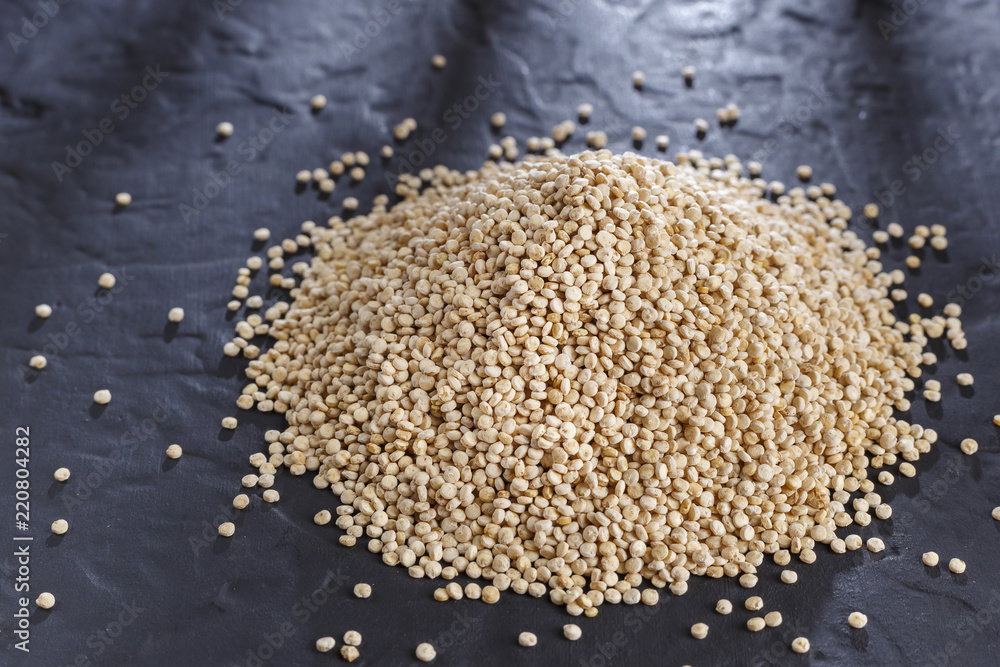 Quinoa grains with spoon and bowl on black background Quinoa grains with spoon and bowl on black background
