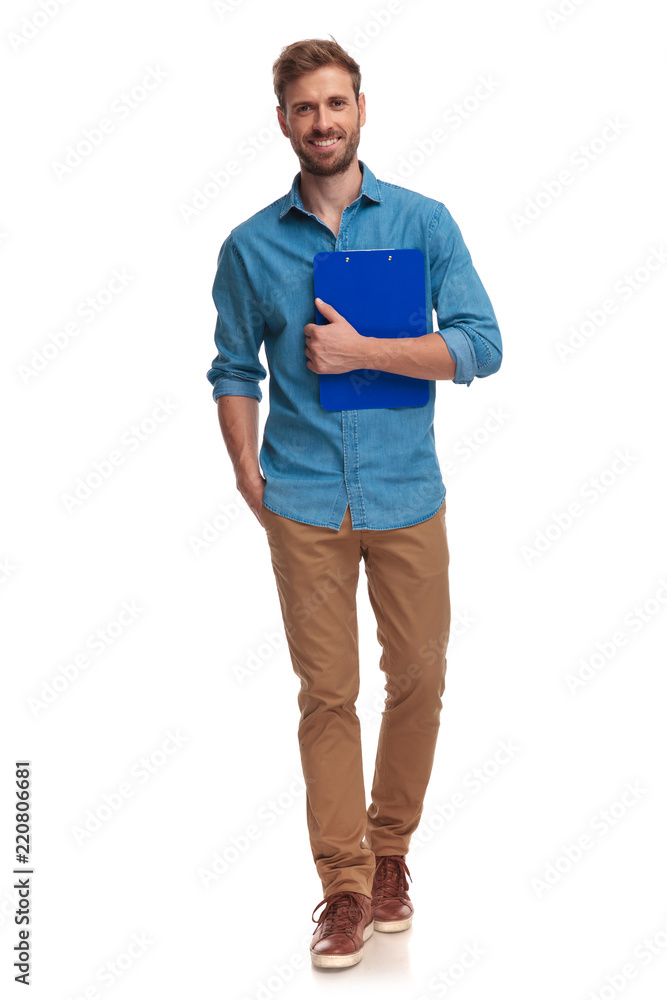 Fototapeta premium young casual student walks forward while holding notepad