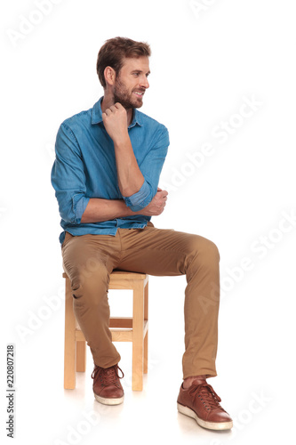 Φωτογραφία pensive young casual man looks to side while sitting