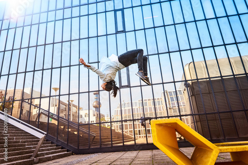 Frau macht Salto mit Spiegelung in Fenstern