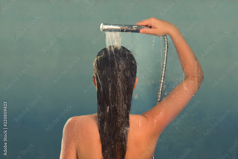 Back view of beautiful naked young woman taking shower in shower cabin. Stock Photo Adobe Stock
