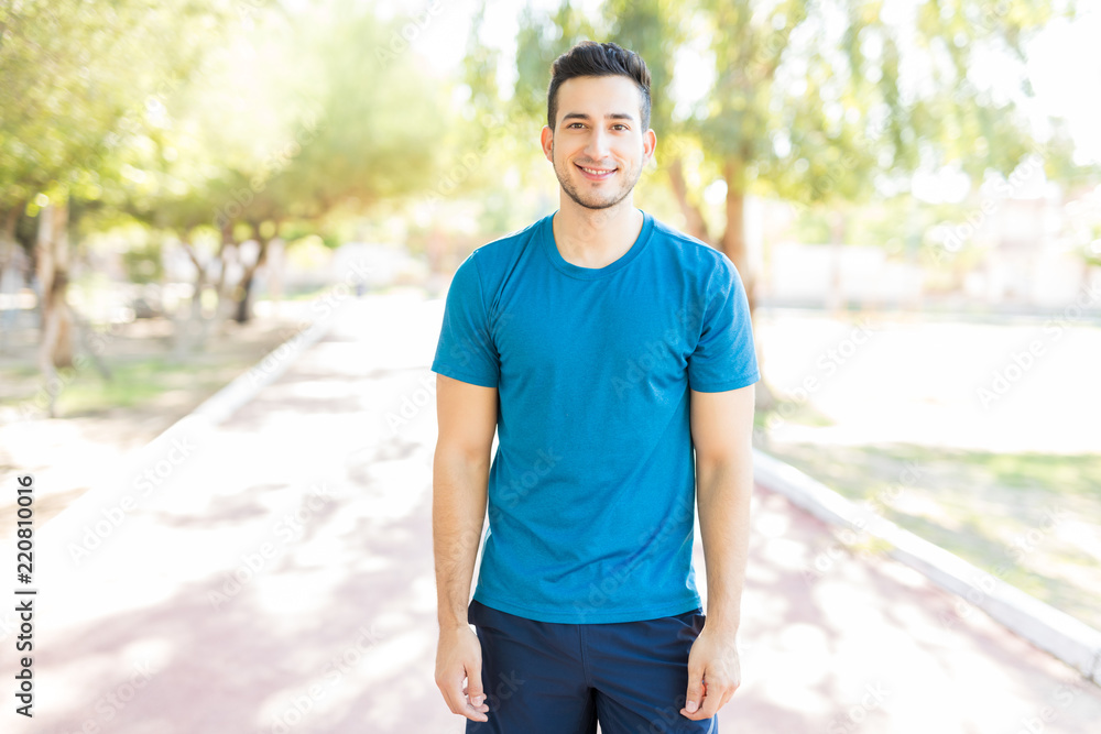 Male Athlete Smiling While Standing On Footpath In Park Male Athlete Smiling While Standing On Footpath In Park