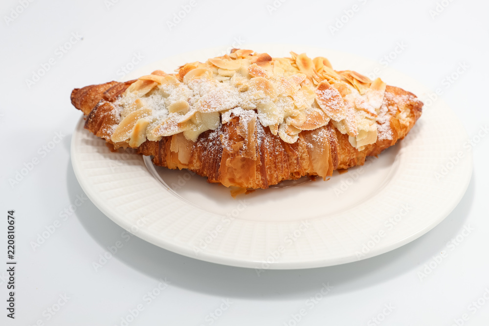 Freshly baked croissant with nuts on a white plate Freshly baked croissant with nuts on a white plate