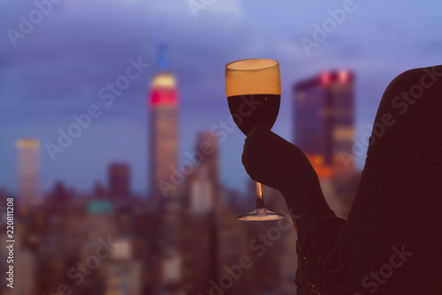 Female hand with glass of wine on Manhattan background. New York city.  Service on the roof of the restaurant photo