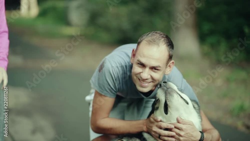 A man in park stroking a dog photo