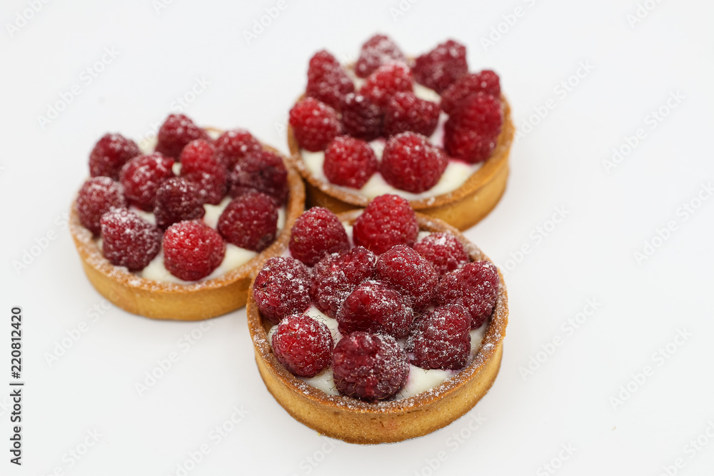 Three tartlets with raspberry on white background Three tartlets with raspberry on white background