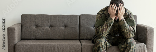 Soldier in uniform sitting on a sofa, waiting for his his appointment with a psychotherapist