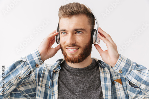 Pleased bearded man in shirt and headphones listening music
