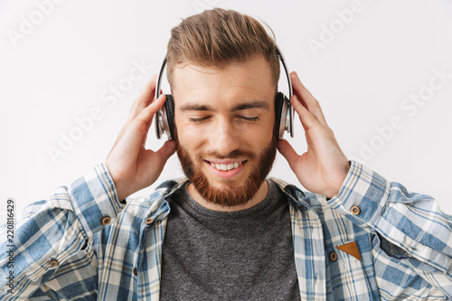 Pleased bearded man in shirt and headphones listening music