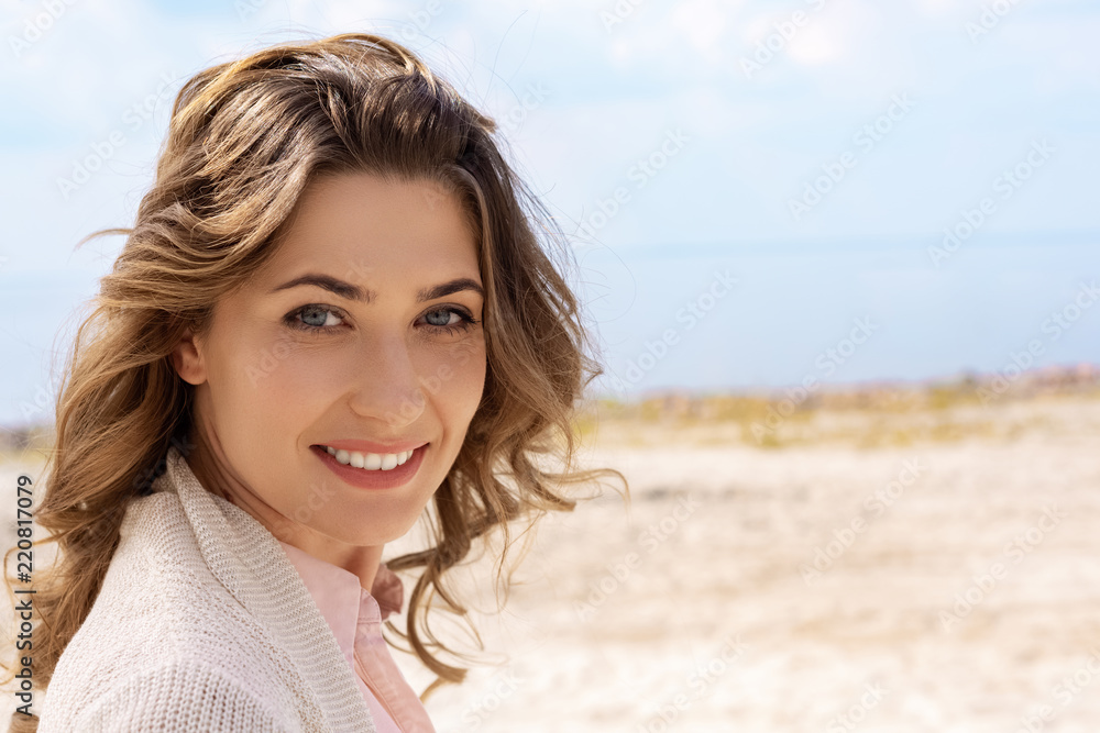 portrait of smiling woman looking at camera on sandy beach portrait of smiling woman looking at camera on sandy beach