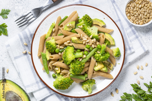 Vegan pasta penne with broccoli, avocado and pine nuts top view.