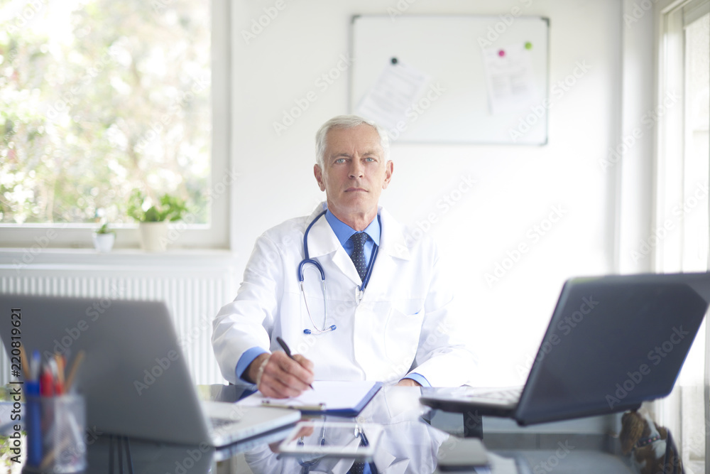 Senior male doctor working at desk in the specialist office Senior male doctor working at desk in the specialist office