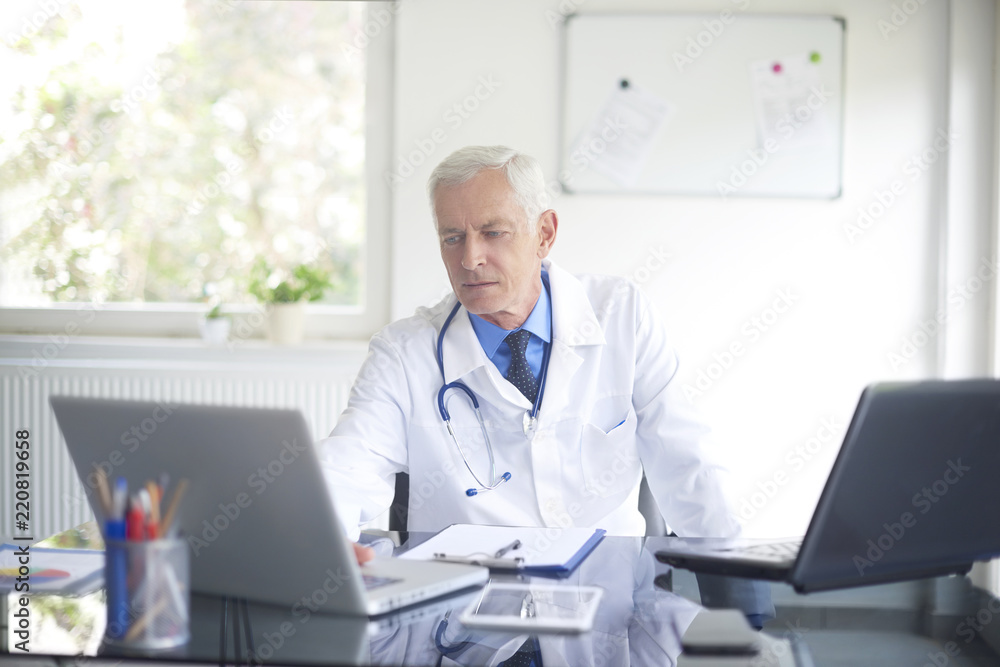 Senior male doctor working at consulting room Senior male doctor working at consulting room