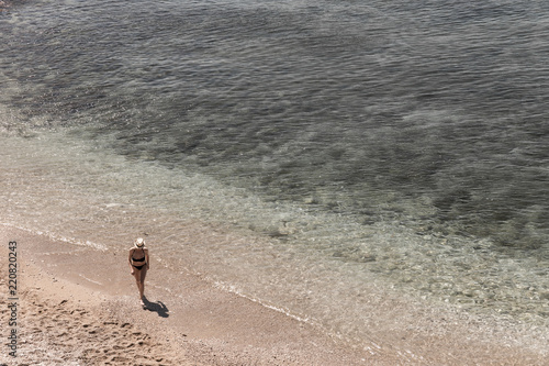 Femme au chapeau marchant sur la plage photo