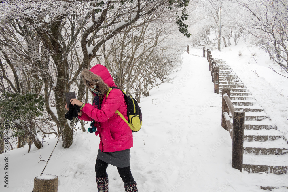 Girl accidentally tourists taking pictures of flowers and trees on beppu ropeway was covered with snow after a blizzard struck hard.