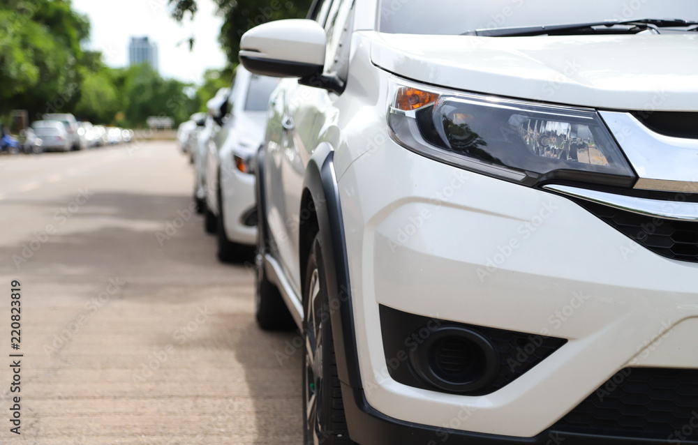 Closeup of front side view of white car parking beside the street in sunny day. 