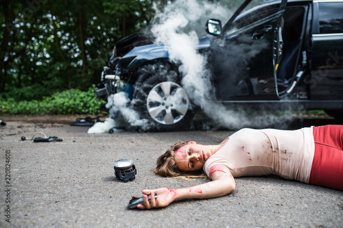 Photography Young injured woman lying on the road after a car accident, unconscious