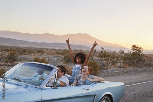 Group Of Friends On Road Trip Driving Classic Convertible Car 