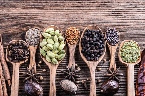 Different types of whole Indian spices in wooden background close-up.