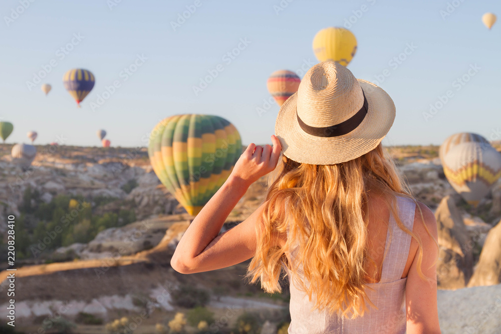 Hipster Traveler with backpack and outspread hands. Enjoying the view of the hot air balloons