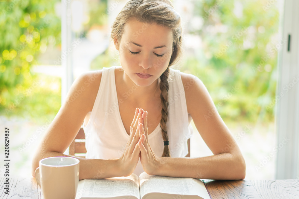 © PhotoGranary - Christian worship and praise. A young woman is reading the Bible and praying in the early morning © PhotoGranary - Christian worship and praise. A young woman is reading the Bible and praying in the early morning