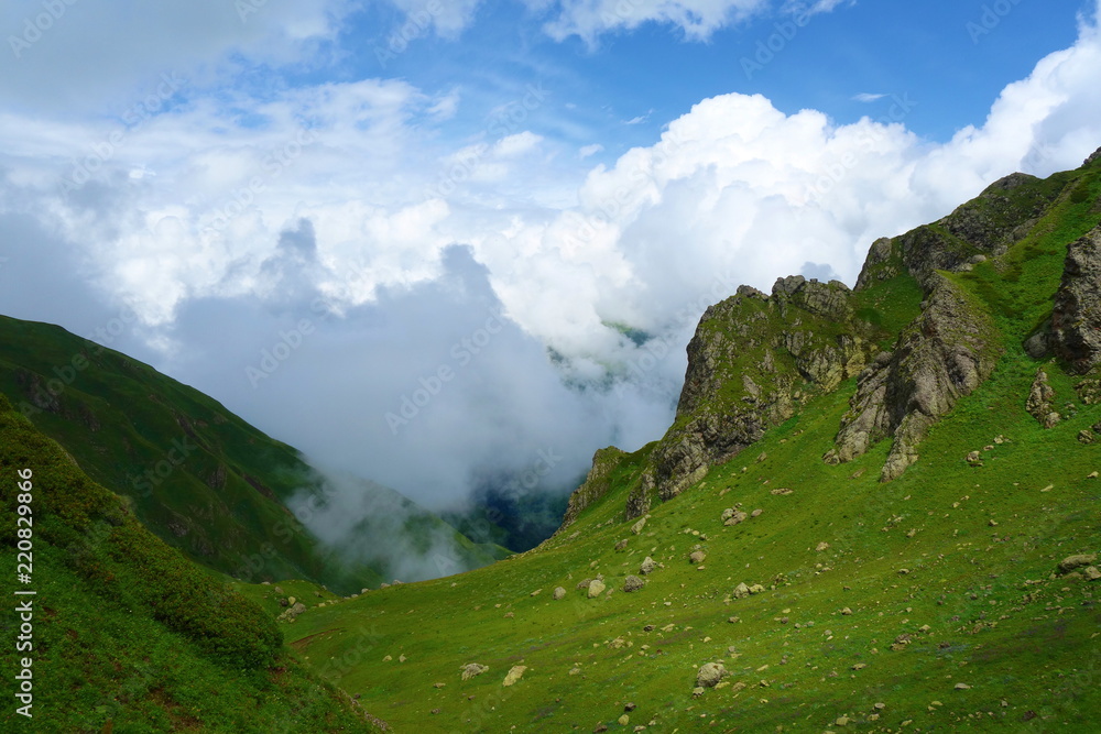 Fototapeta premium Hiking trail to Silver lakes with clouds around the mountains going via Tobavarchkhili from Mukhuri to Khaishi in Caucasus mountains, Georgia
