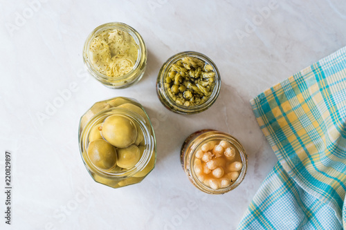 Jars of Pickled Vegetables Green and White Asparagus, Artichoke Heart and Unripe Green Almond Pickles in Glass Bottle. photo