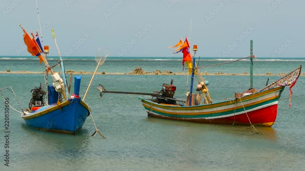 Tropical ocean beach landscape with moored small wooden traditional colorful fishing boat. Seascape near asian poor Muslim fisherman village on Koh Samui island in Thailand. Flags and lamps aboard. Tropical ocean beach landscape with moored small wooden traditional colorful fishing boat. Seascape near asian poor Muslim fisherman village on Koh Samui island in Thailand. Flags and lamps aboard.