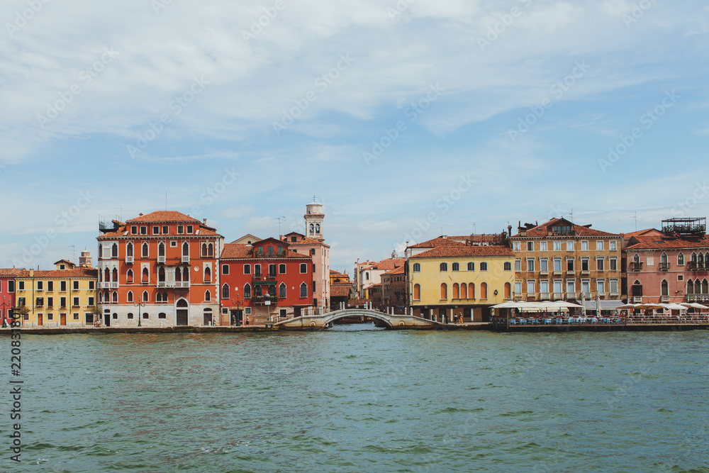 Venetian channel view at the city in one horizontal line of urban architecture, buildings, one of the Venice Bridge, free space