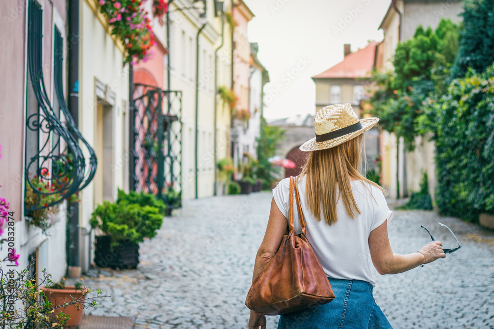 Woman wearing jeans jacket and straw hat. Female tourist walking in the city streets of Olomouc, Czech Republic
