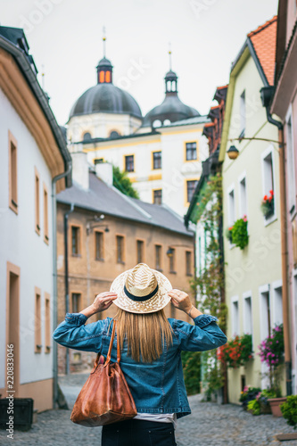 Woman wearing jeans jacket and straw hat. Female tourist walking in the city streets of Olomouc, Czech Republic